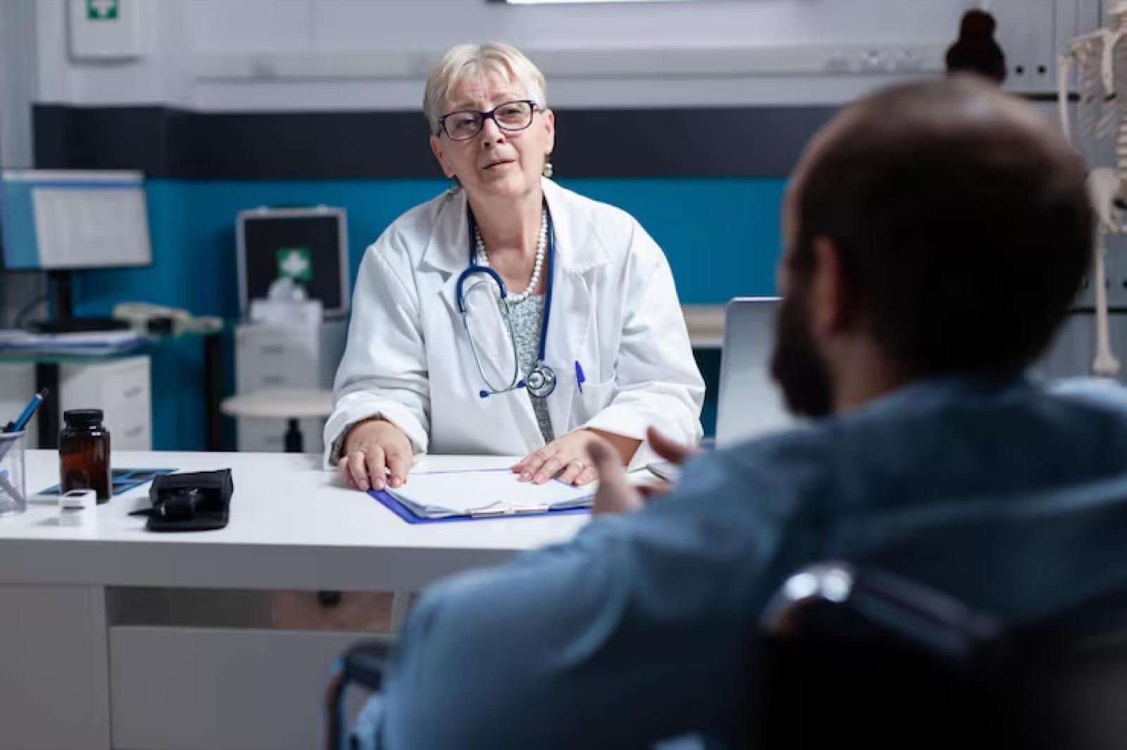 A doctor at her desk speaks with a patient